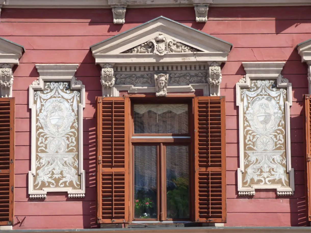 Window with white stucco on a pink facade