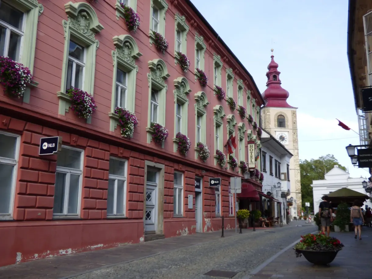 Cobbled street lined with a long red building, bell tower at the end