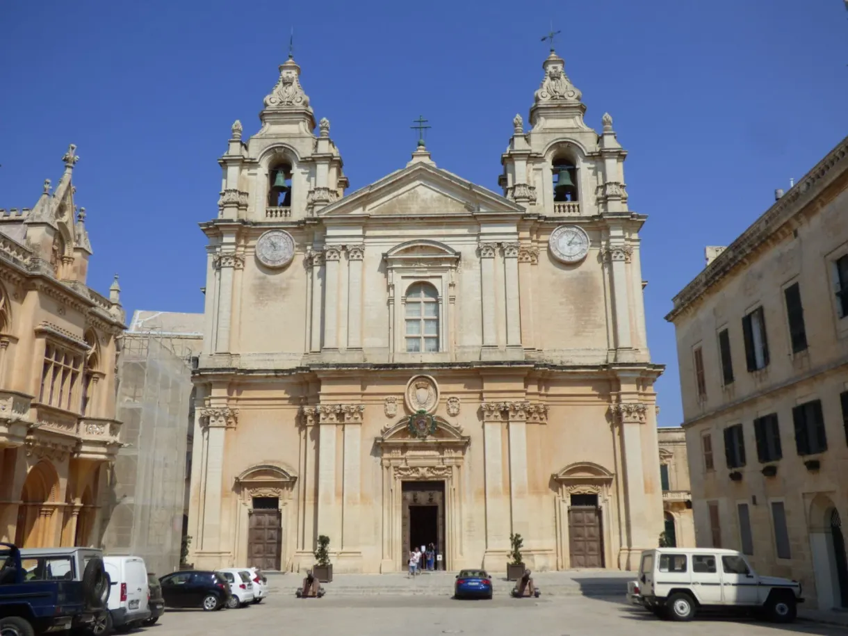 Place pavée et voitures devant les deux clochers de la cathédrale