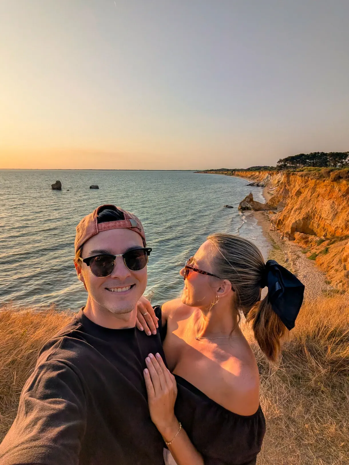 Marie and Romain, the blog's authors, at sunset on a coastline of ochre cliffs