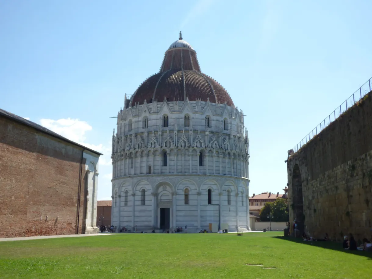 Brown dome of the baptistery above a brick wall