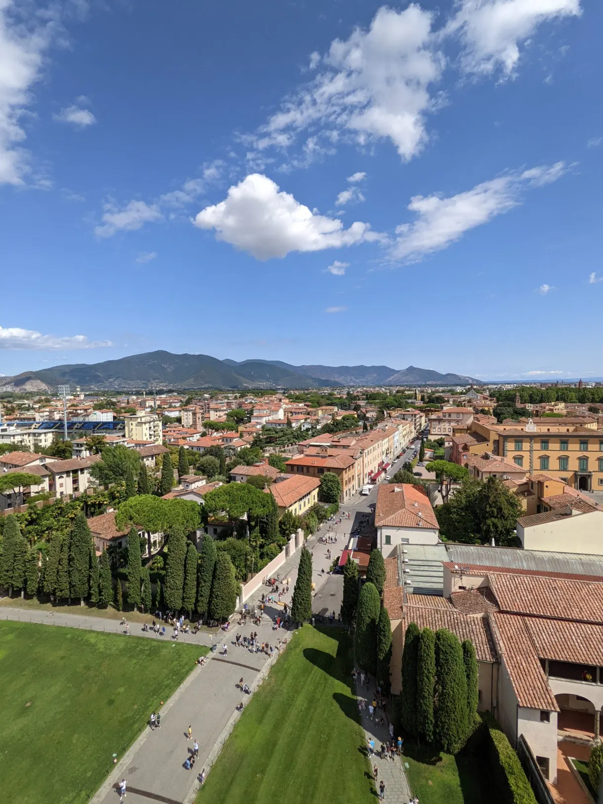 Streets and rooftops of Pisa unrolling all the way to the hills