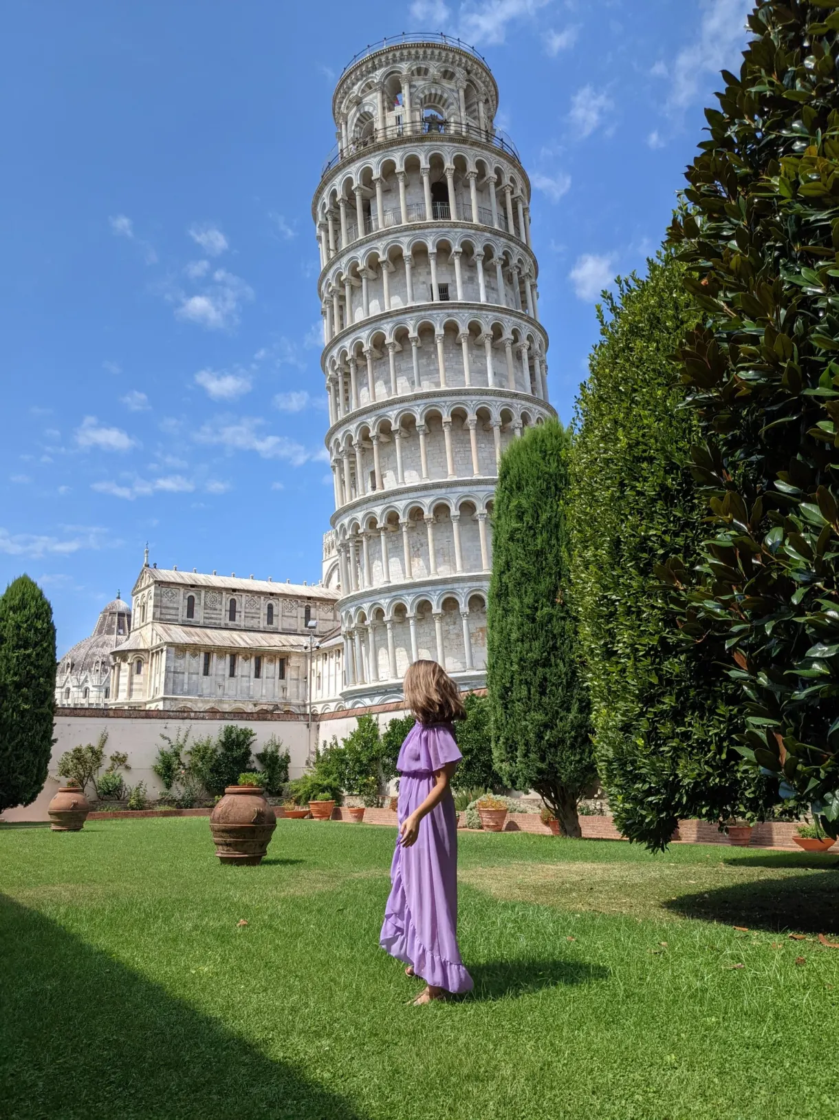 Woman in a purple dress on the lawn at the foot of the tower