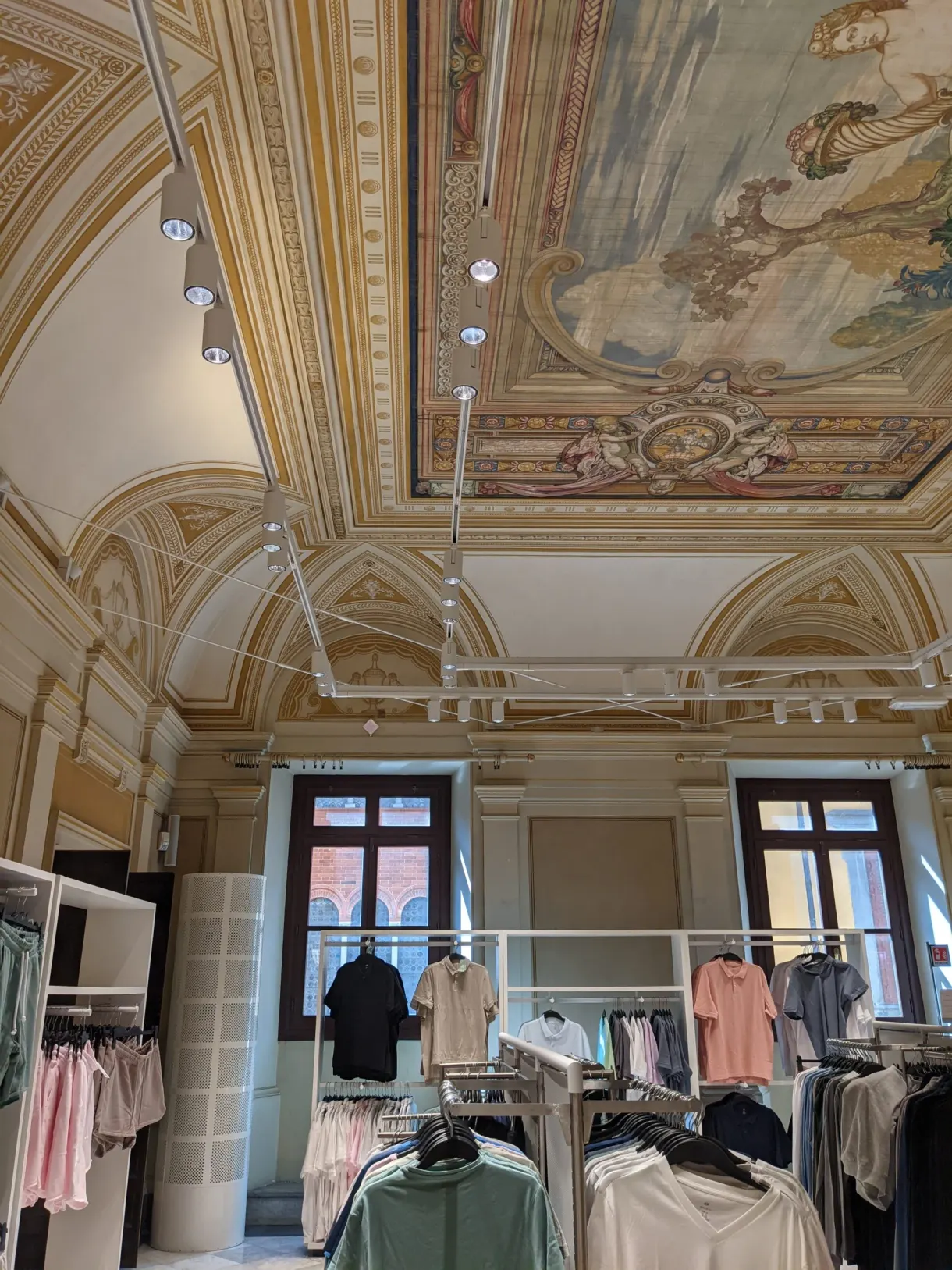 Clothing rails set up beneath a frescoed ceiling