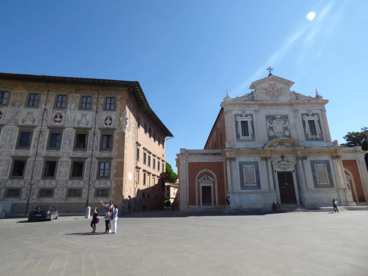 Palace with an ornate facade and a pale church on a paved square