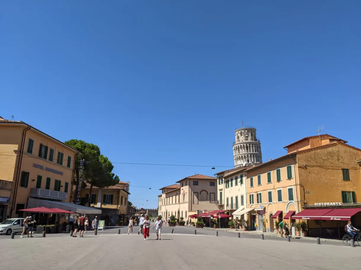 Leaning tower glimpsed at the end of a square lined with terraces