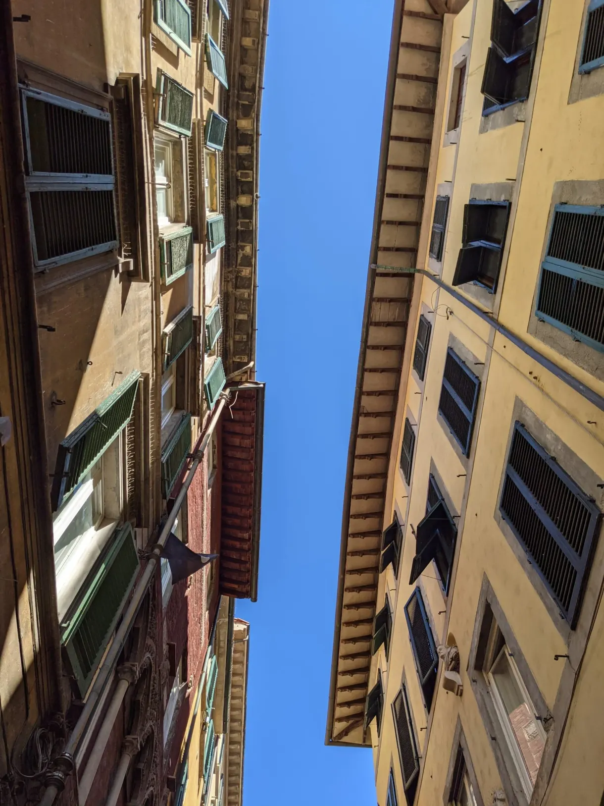 Narrow strip of sky between two facades with green shutters