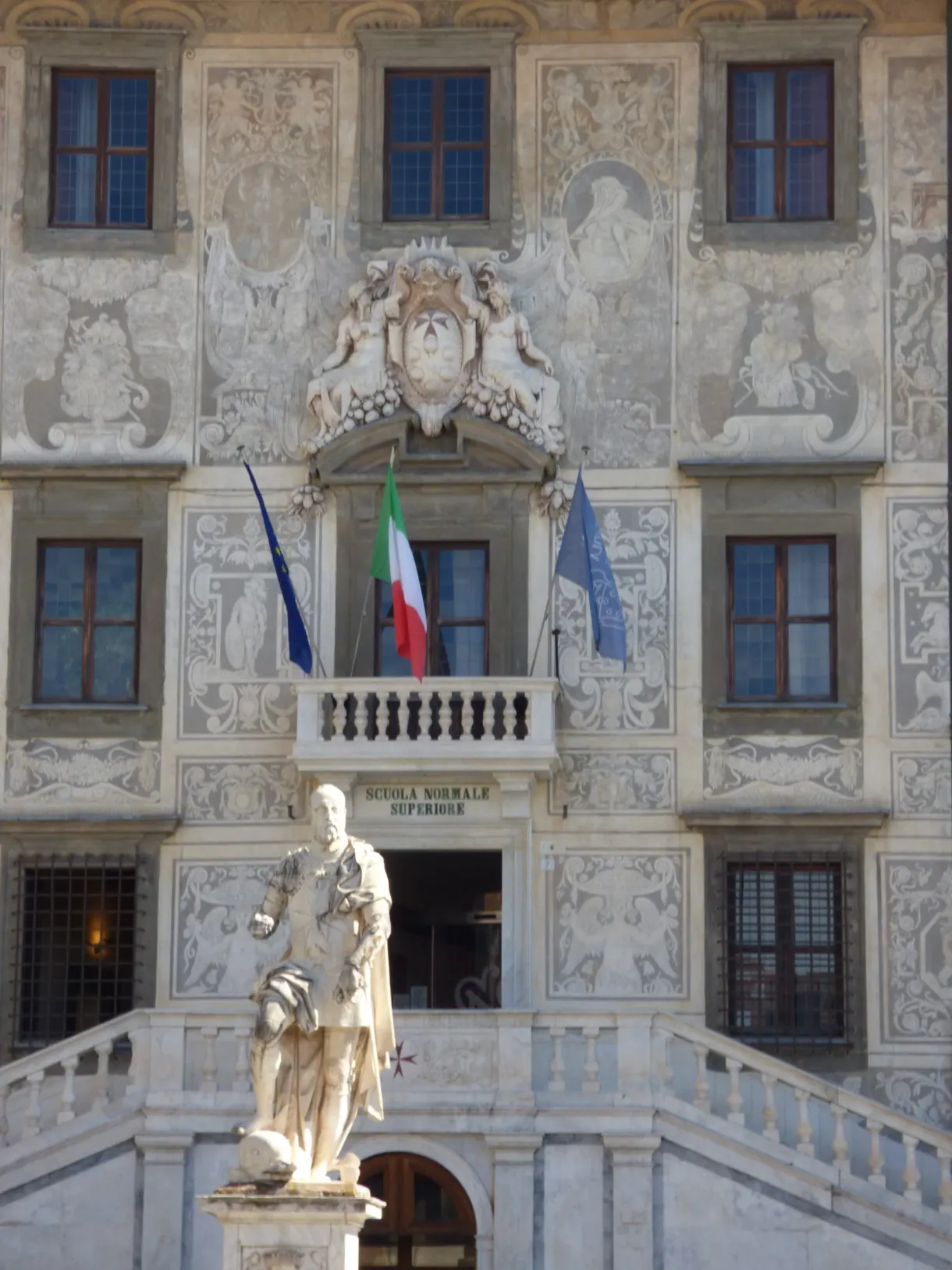 Facade decorated with sgraffito, a statue and flags on the balcony