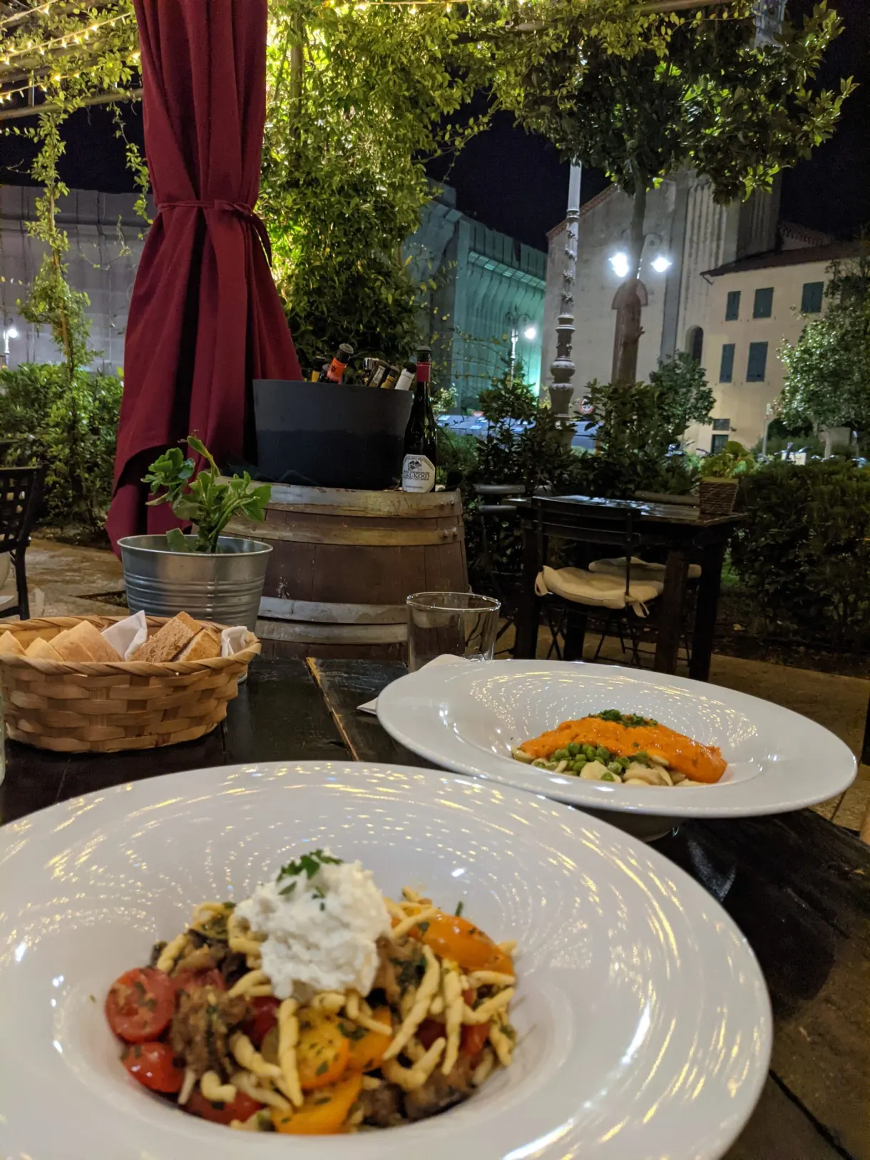 Two plates of pasta on a terrace table in the evening