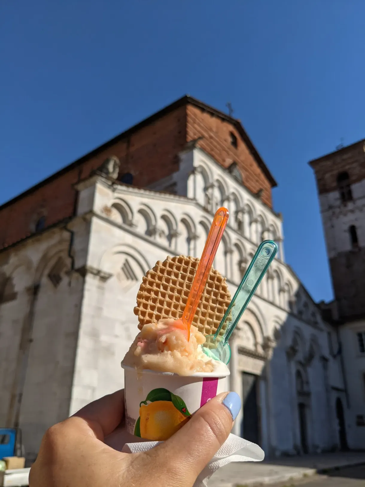 Two scoop ice cream held up in front of a marble church