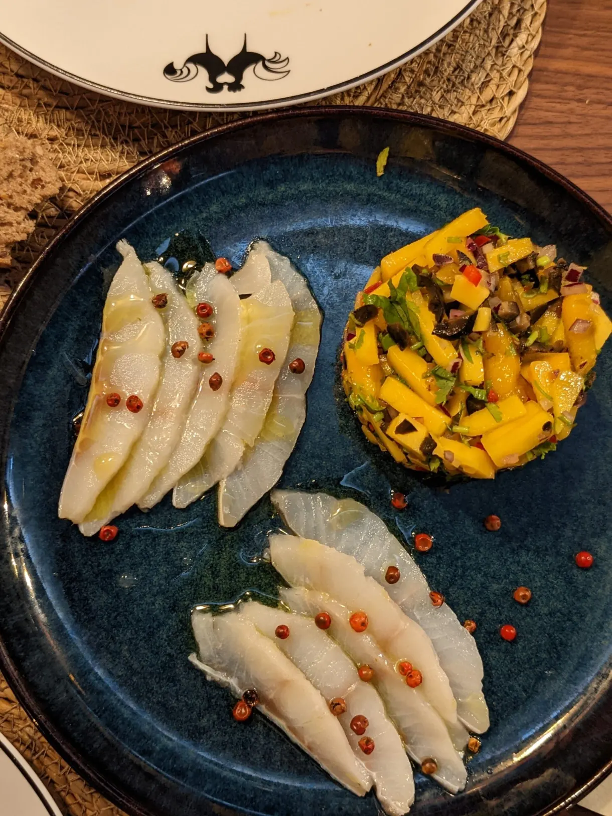 Poisson cru et tartare de mangue sur assiette bleue
