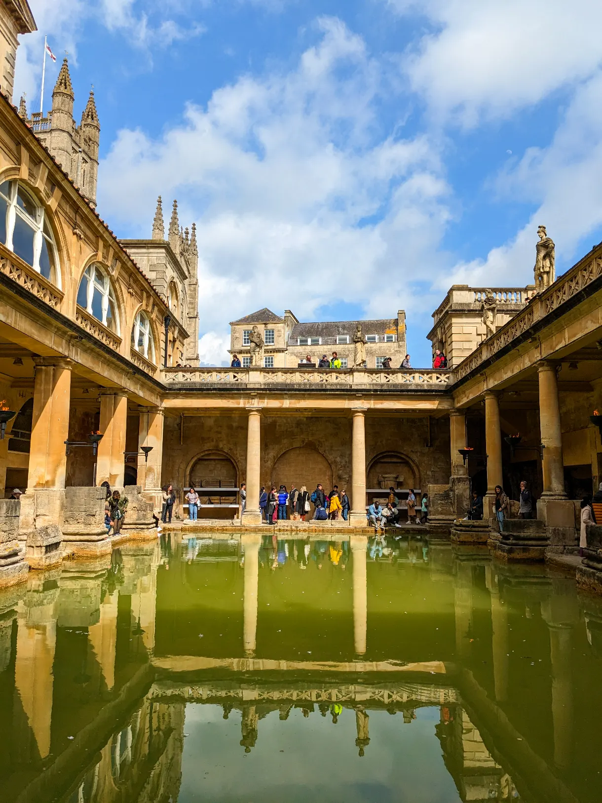 Roman Baths in Bath with green water in the sunshine, reflection in the water