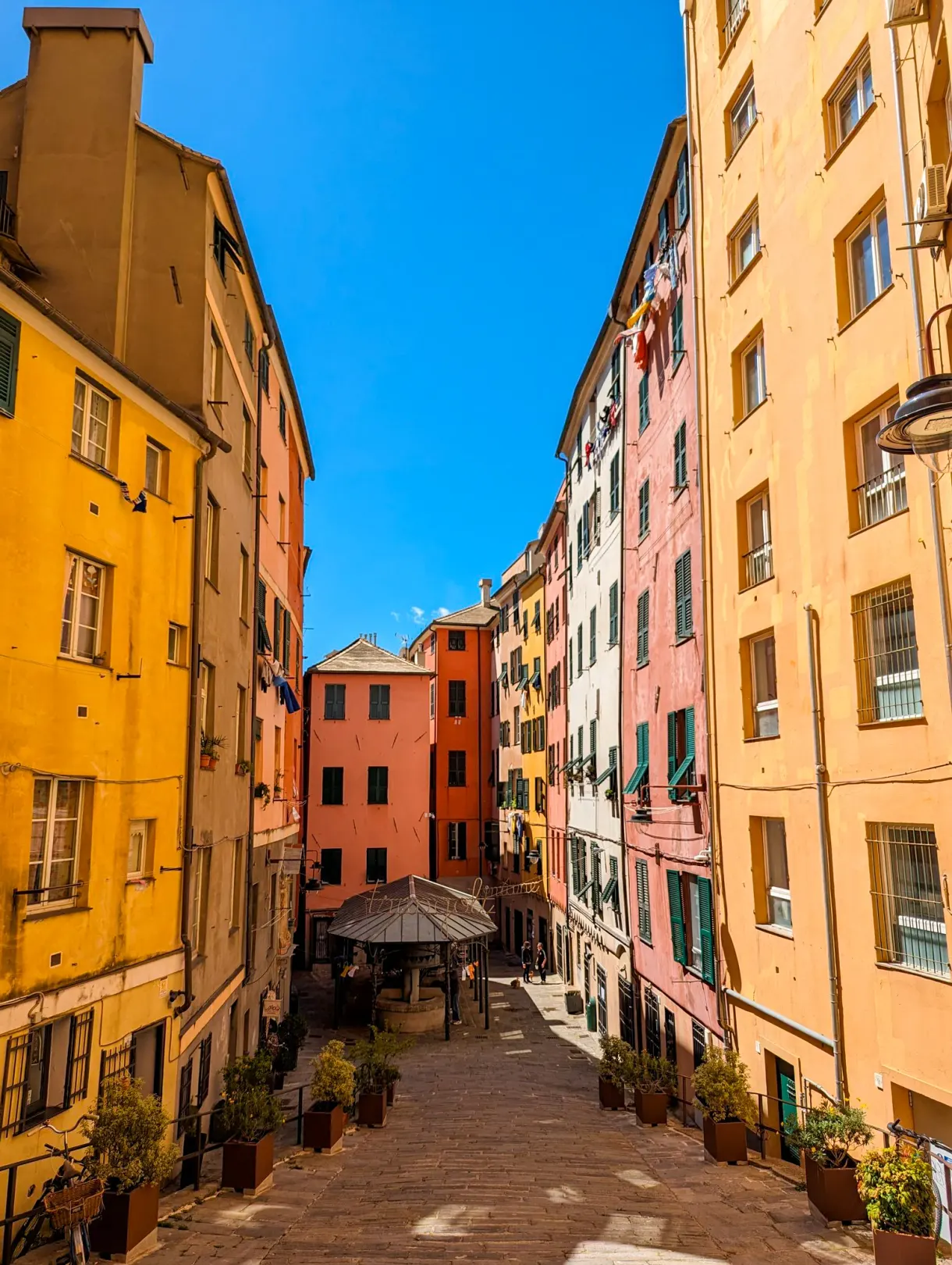 Narrow lane lined with ochre and pink facades in Genoa