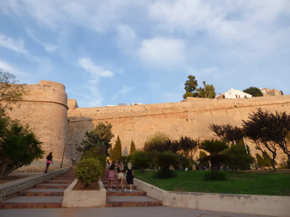 Golden stone bastion of Dalt Vila and its flower lined staircase