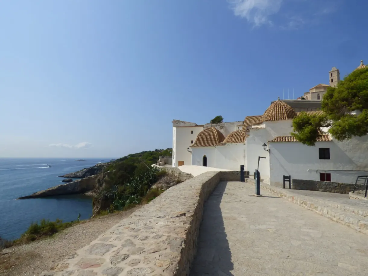 Paved ramp running along a white chapel facing the sea
