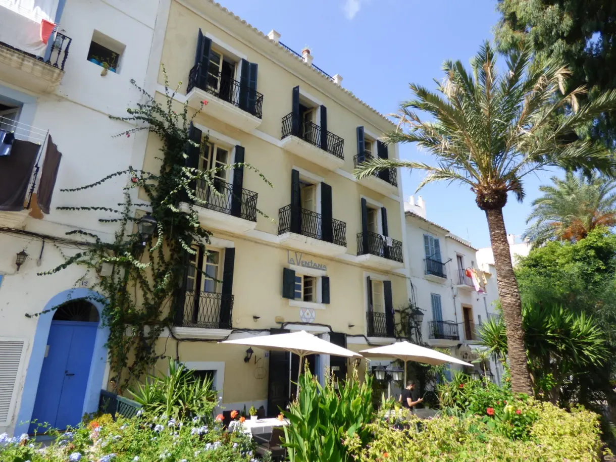 Yellow building with iron balconies and a shaded terrace
