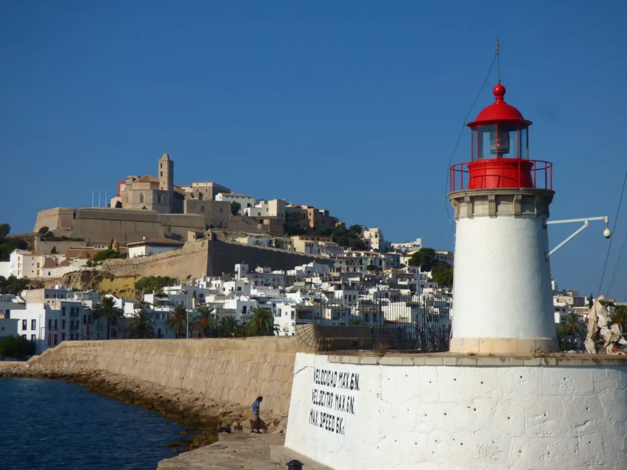 White lighthouse with a red lantern guarding the harbour entrance
