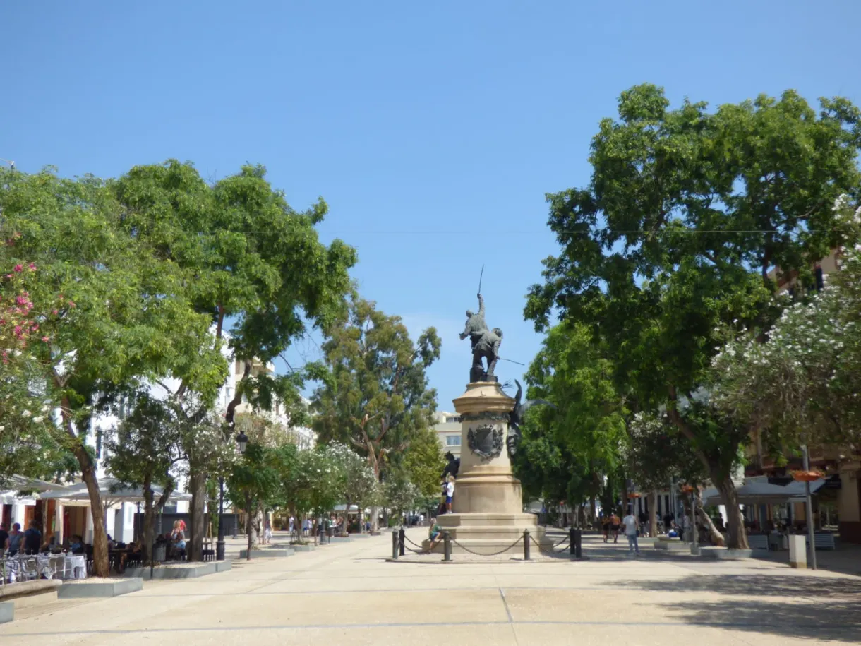 Bronze monument in the middle of a tree lined promenade