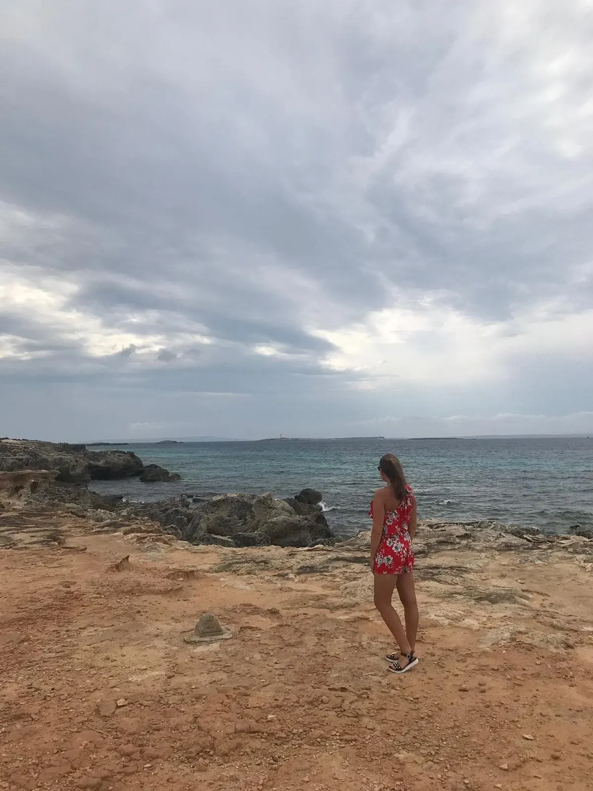 Silhouette in a red dress on a beach of sand and rock