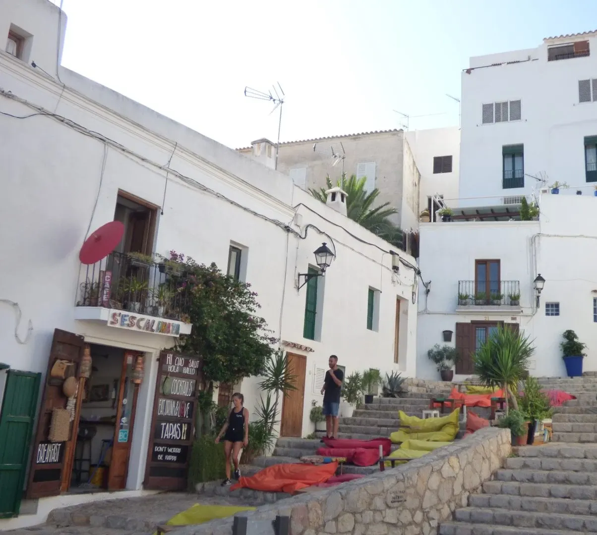 Colourful cushions set on the steps in front of a white restaurant