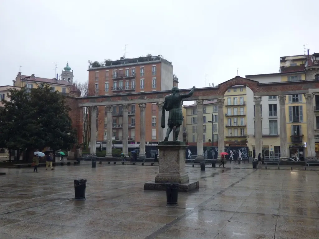 Statue de bronze au centre d'une place pavée détrempée