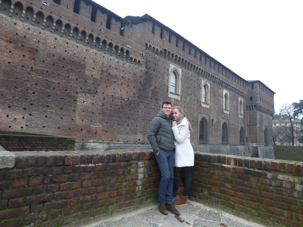Couple posant contre le muret de brique du château