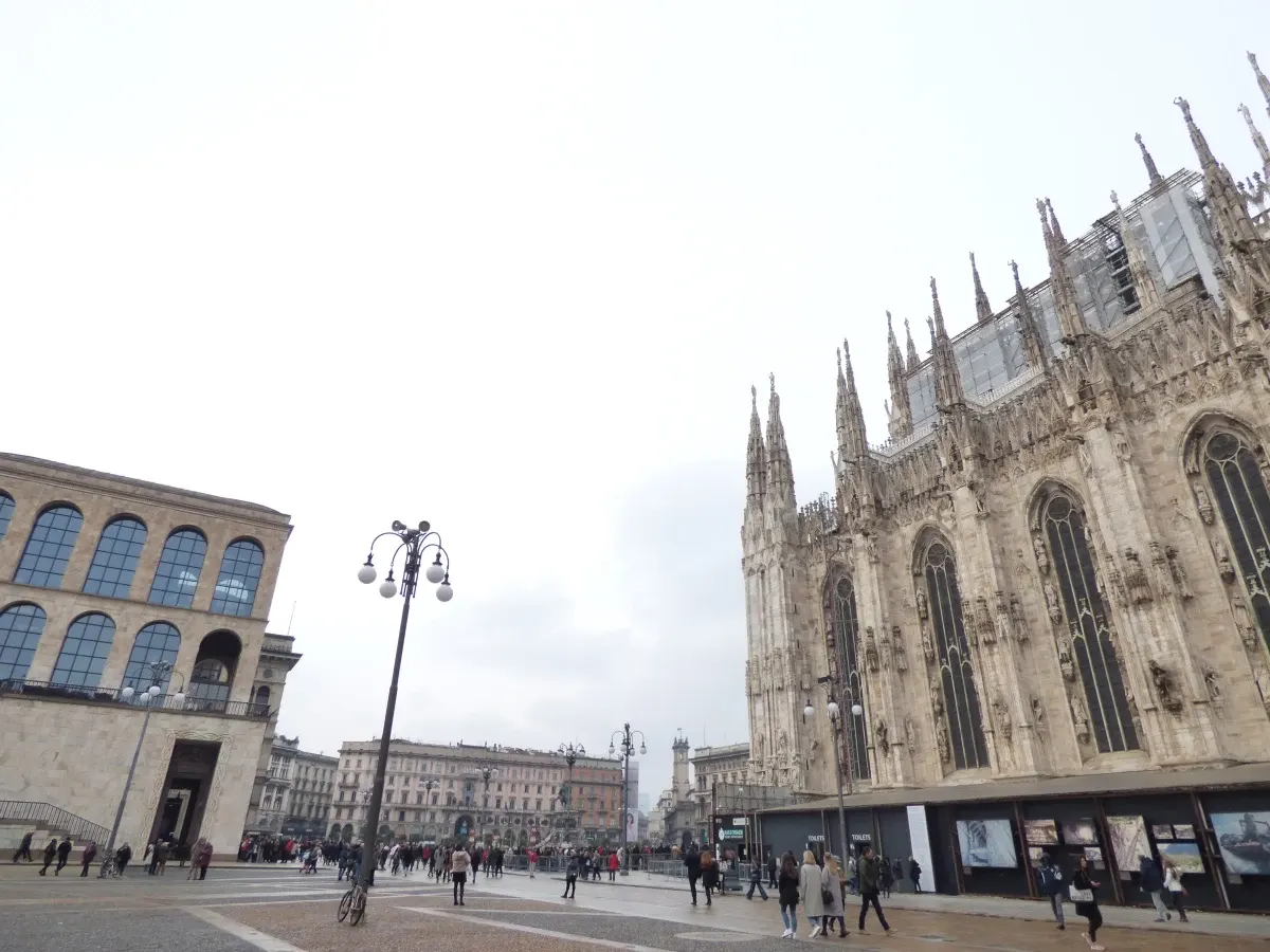 Place du Dôme et flanc de la cathédrale sous un ciel gris