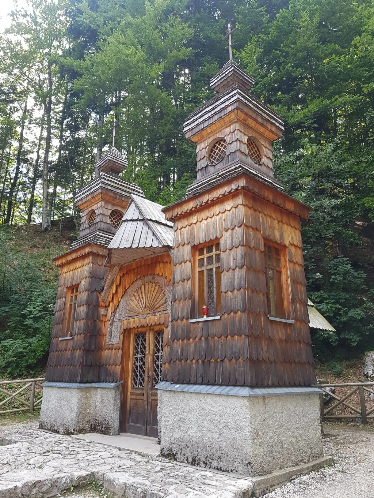 Wooden Russian chapel with two bell towers beneath the fir trees