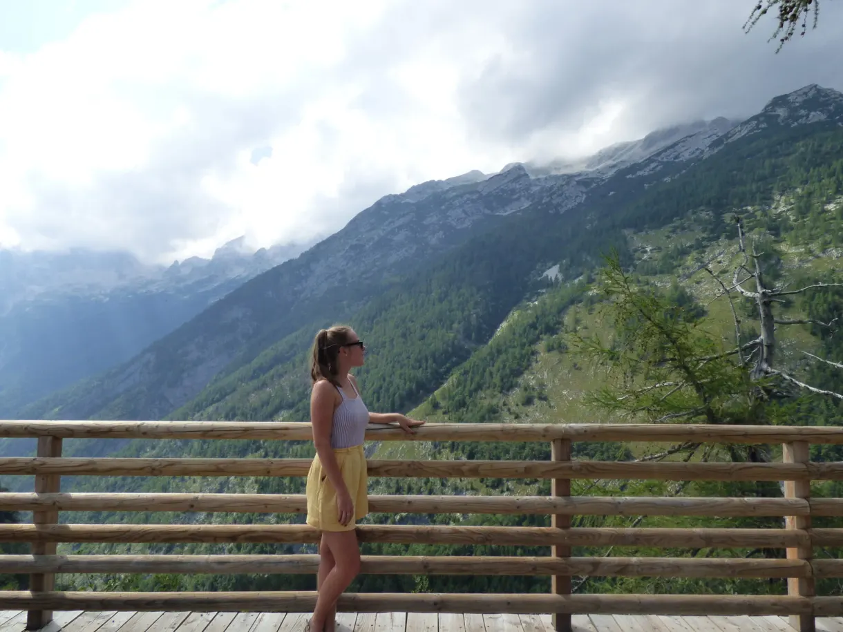 Woman leaning on a wooden railing facing the valley