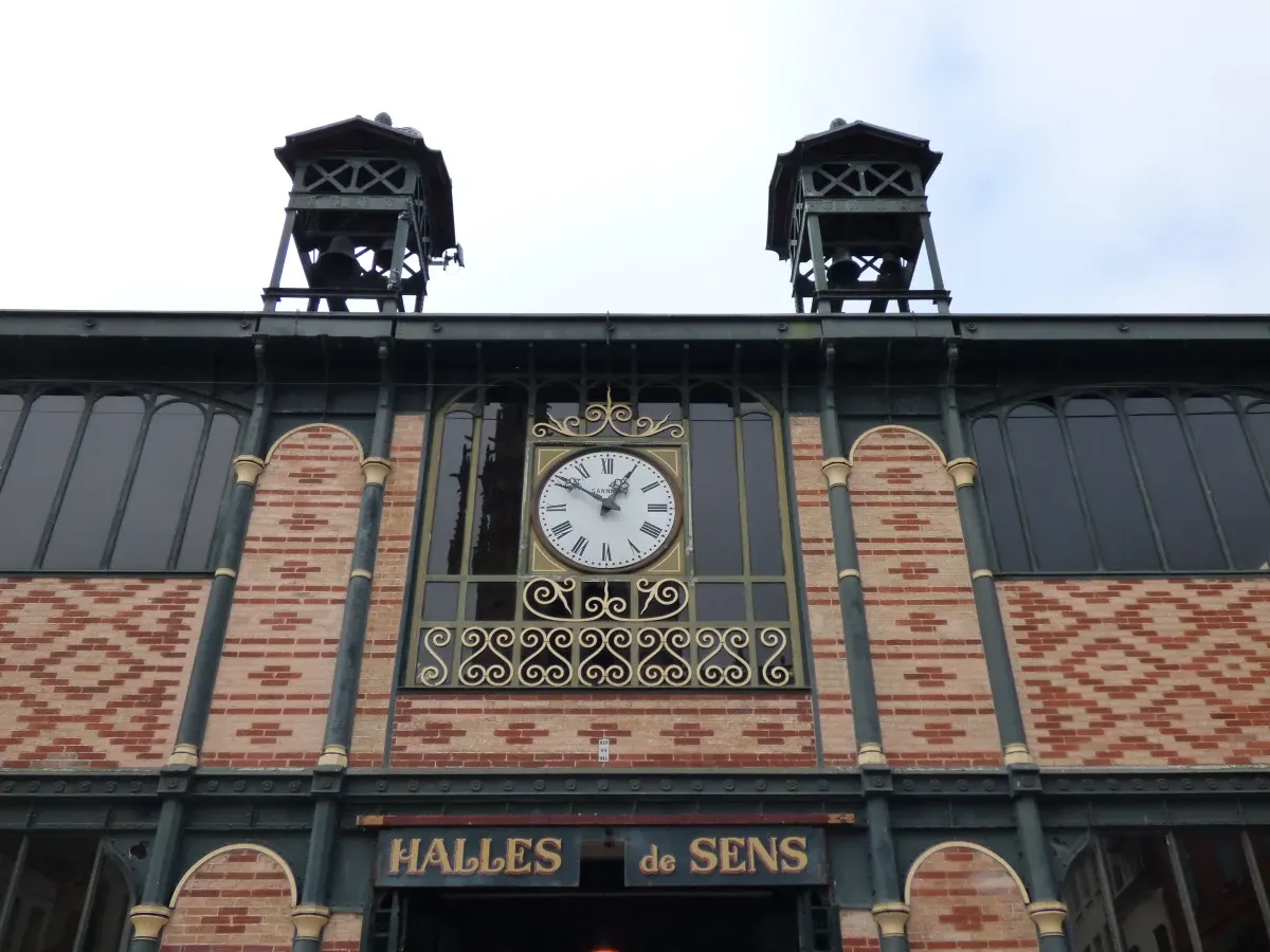 Clock and ironwork on the facade of the market hall of Sens