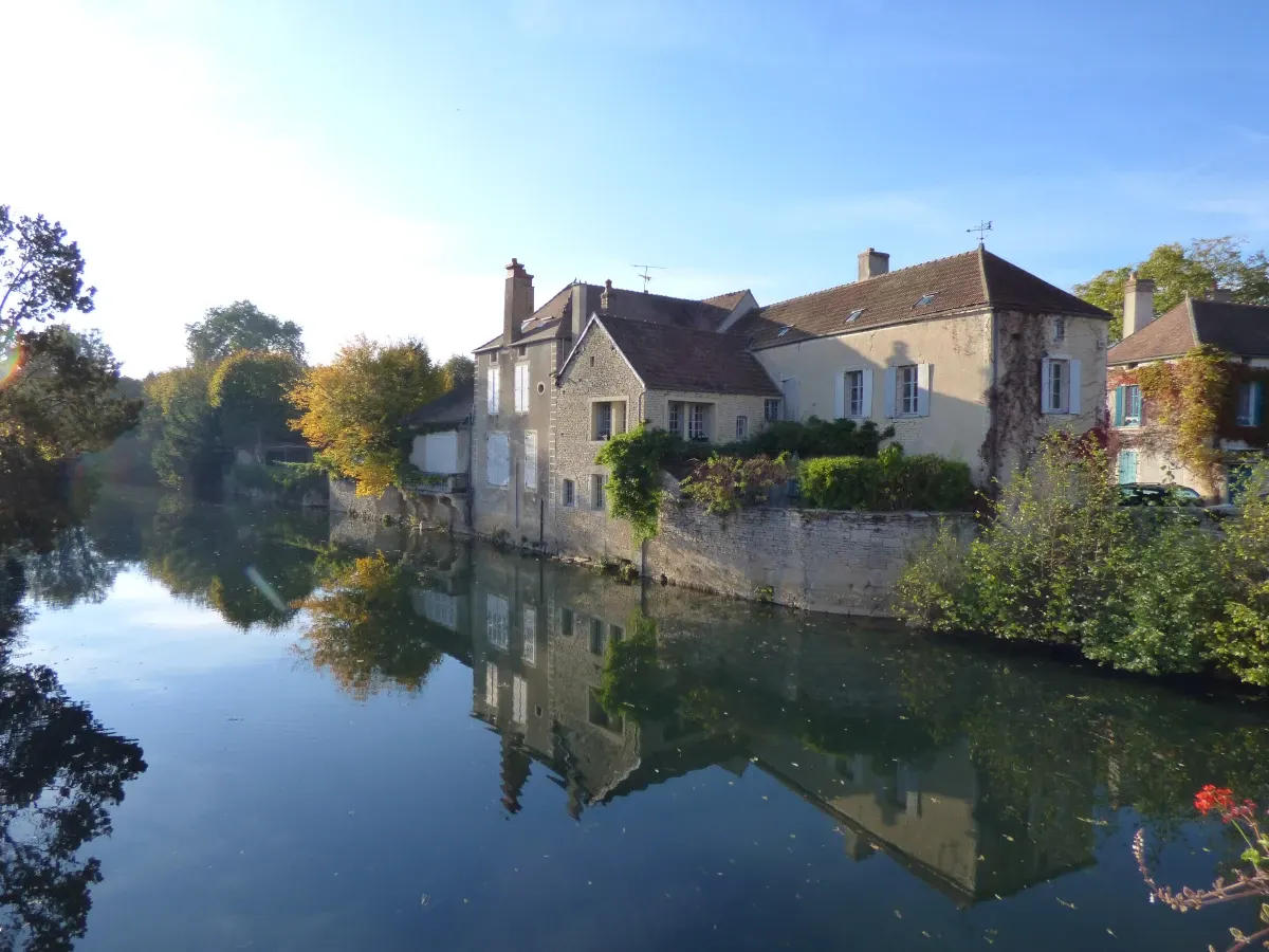 Old houses reflected in the tree-lined river