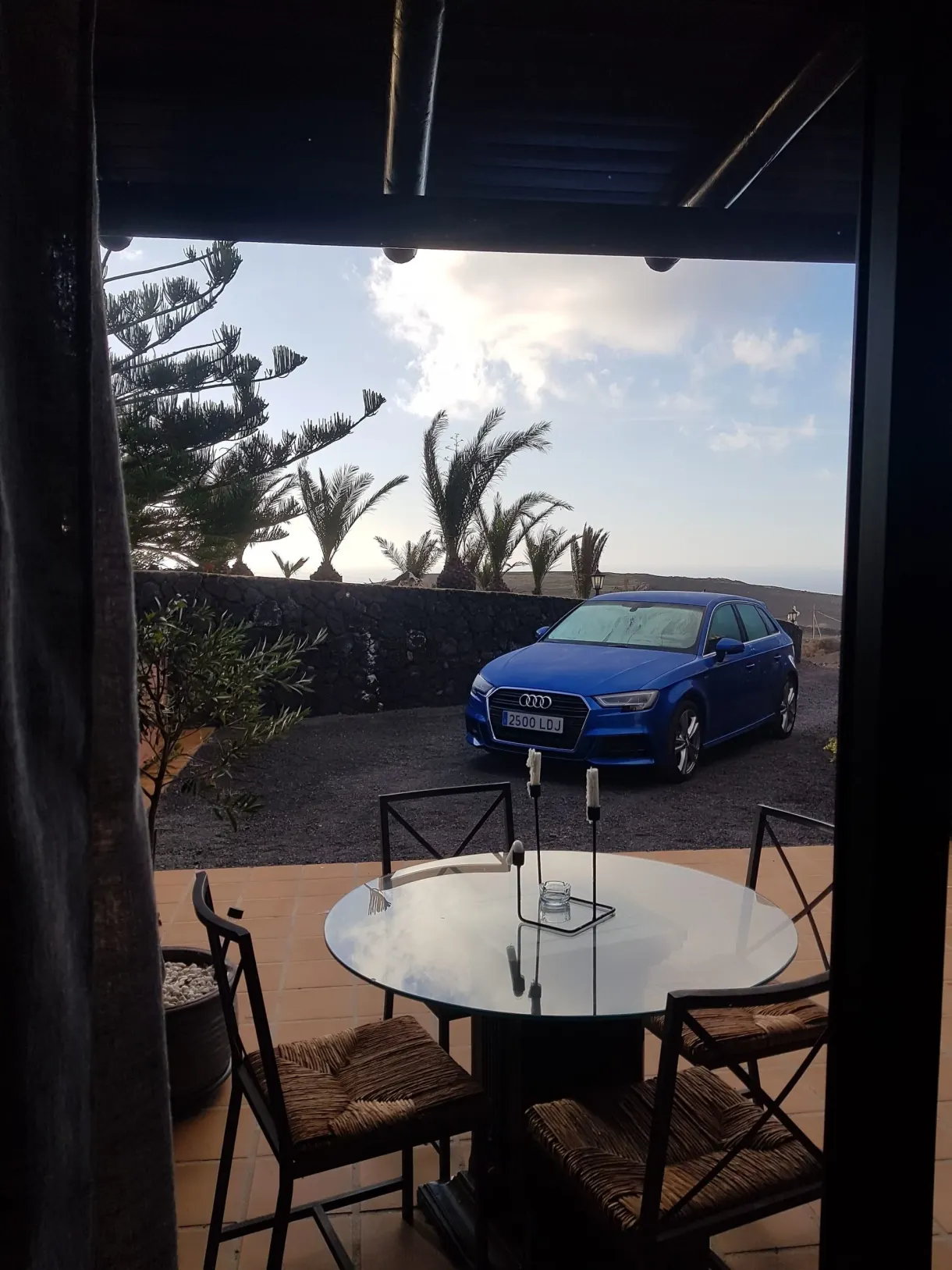 Sheltered terrace with a round table and a blue car parked in front