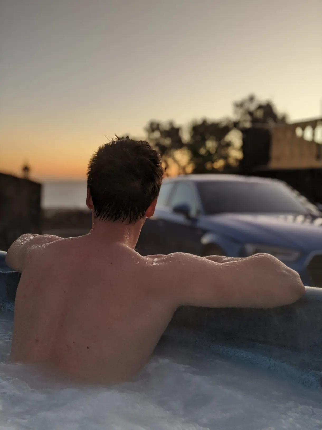 Man seen from behind in the hot tub at dusk