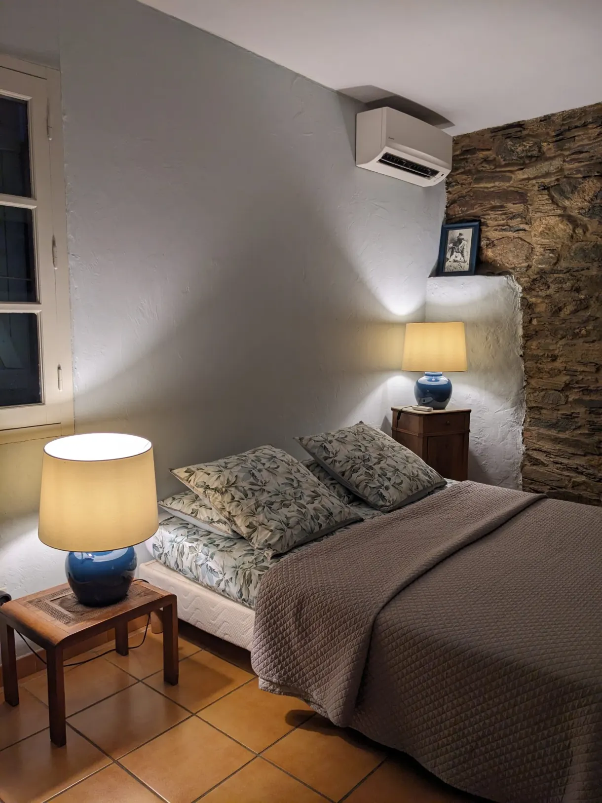 Bedroom with stone walls lit by two bedside lamps