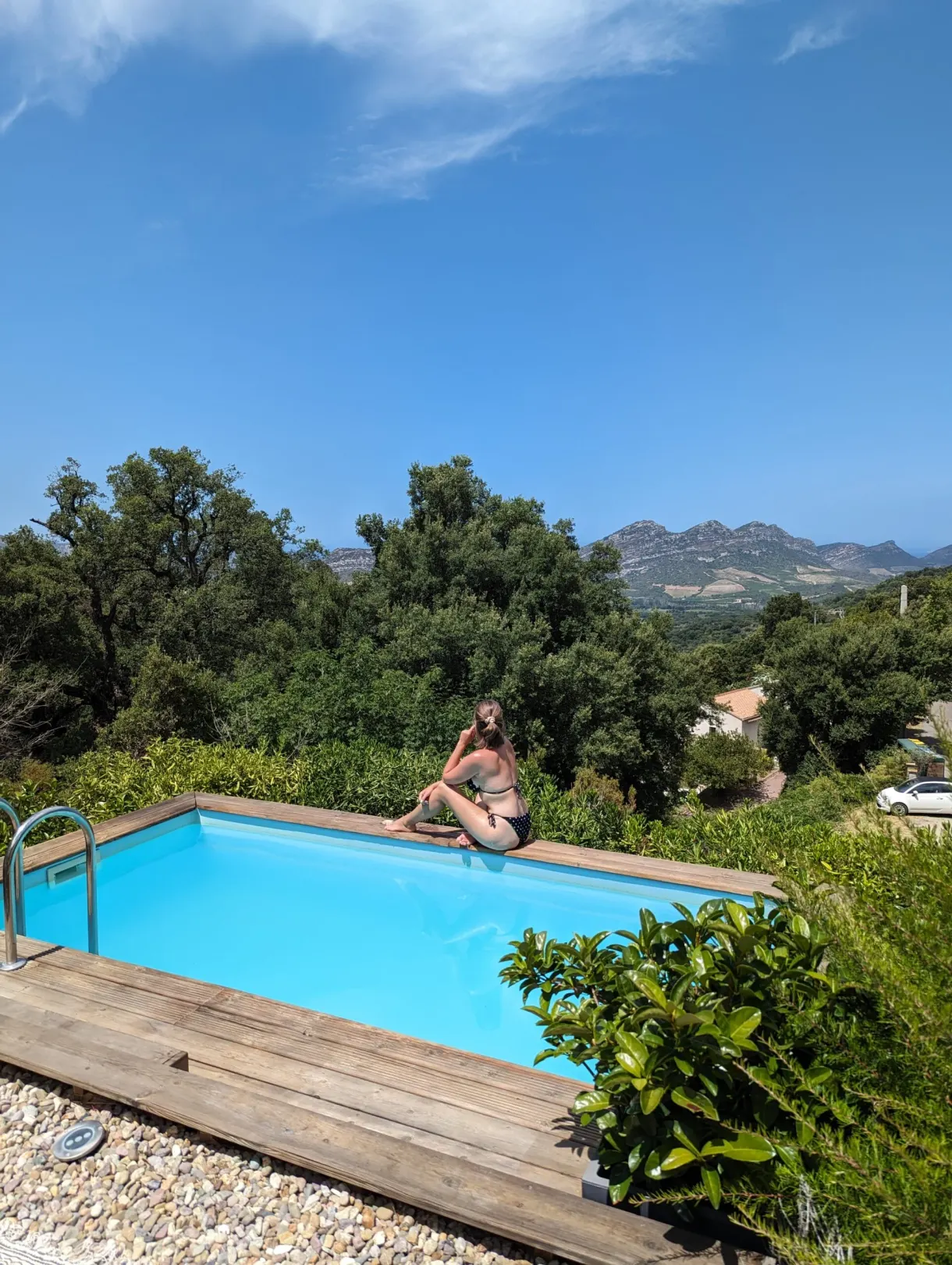 Swimmer sitting at the edge of the pool facing the mountains