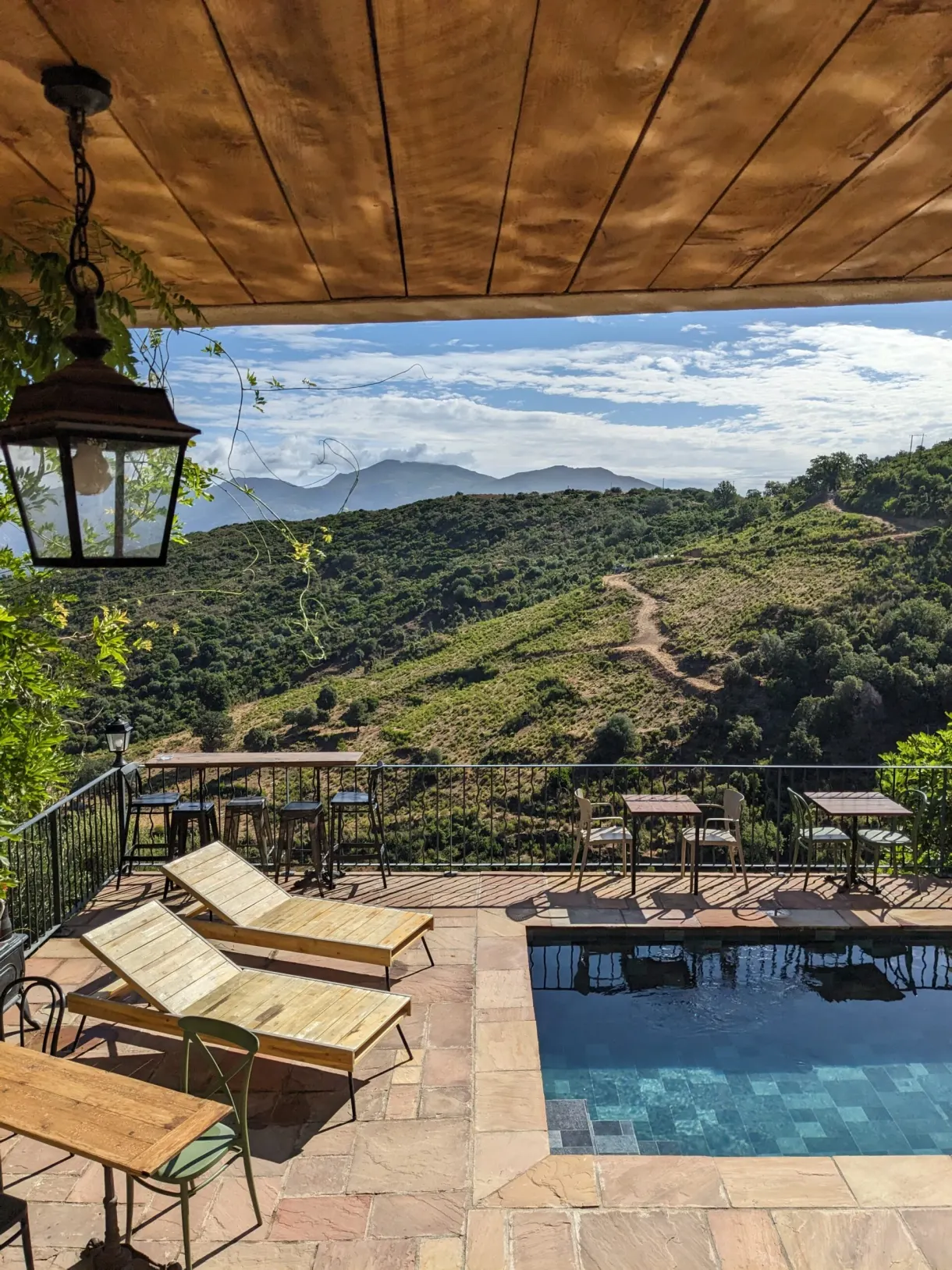 Covered terrace, sun loungers and pool facing the hills