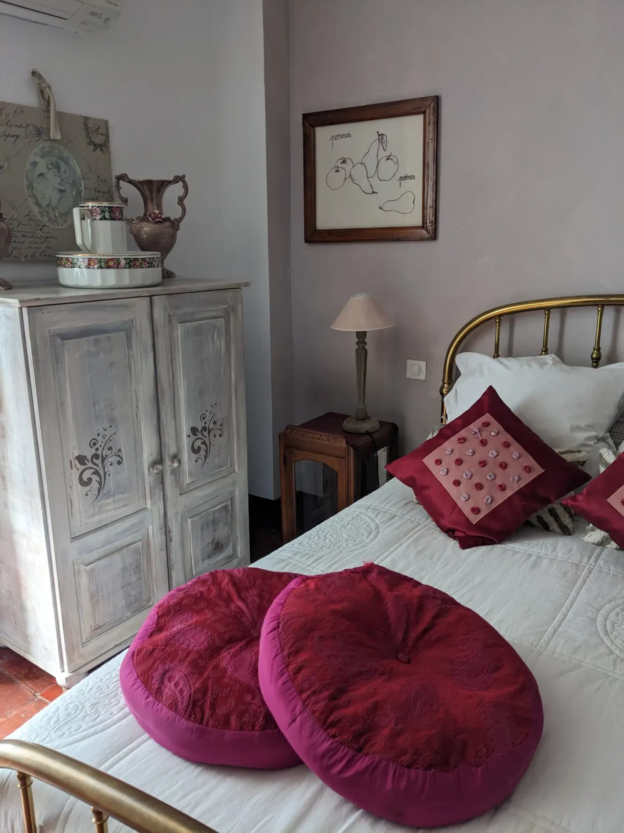 Red cushions and an antique wardrobe in a weathered bedroom