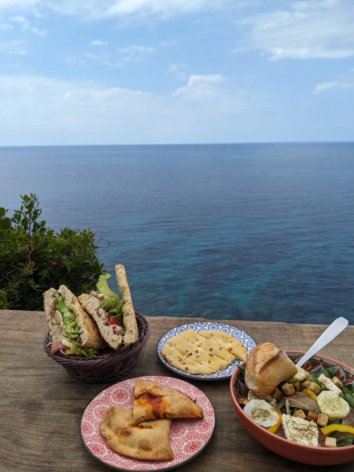 Fritters and marinated vegetables on a table above the sea