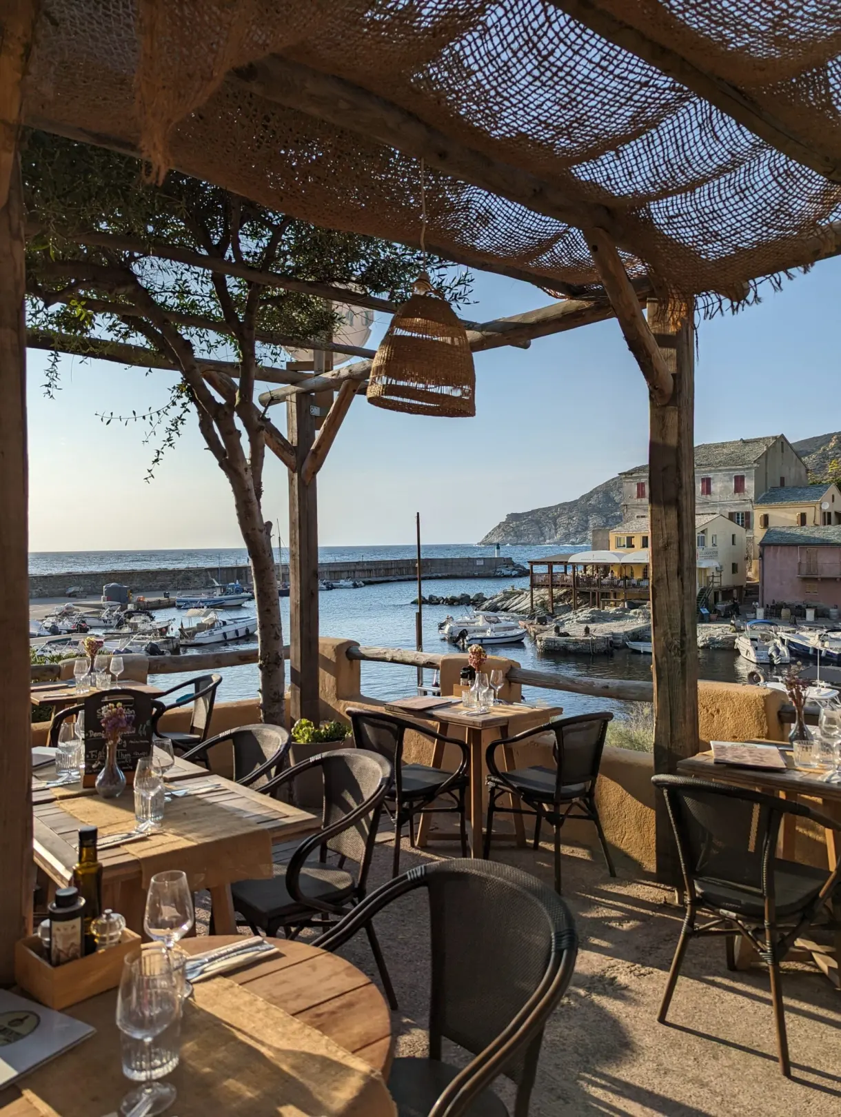 Terrace under a pergola looking onto a small fishing harbour