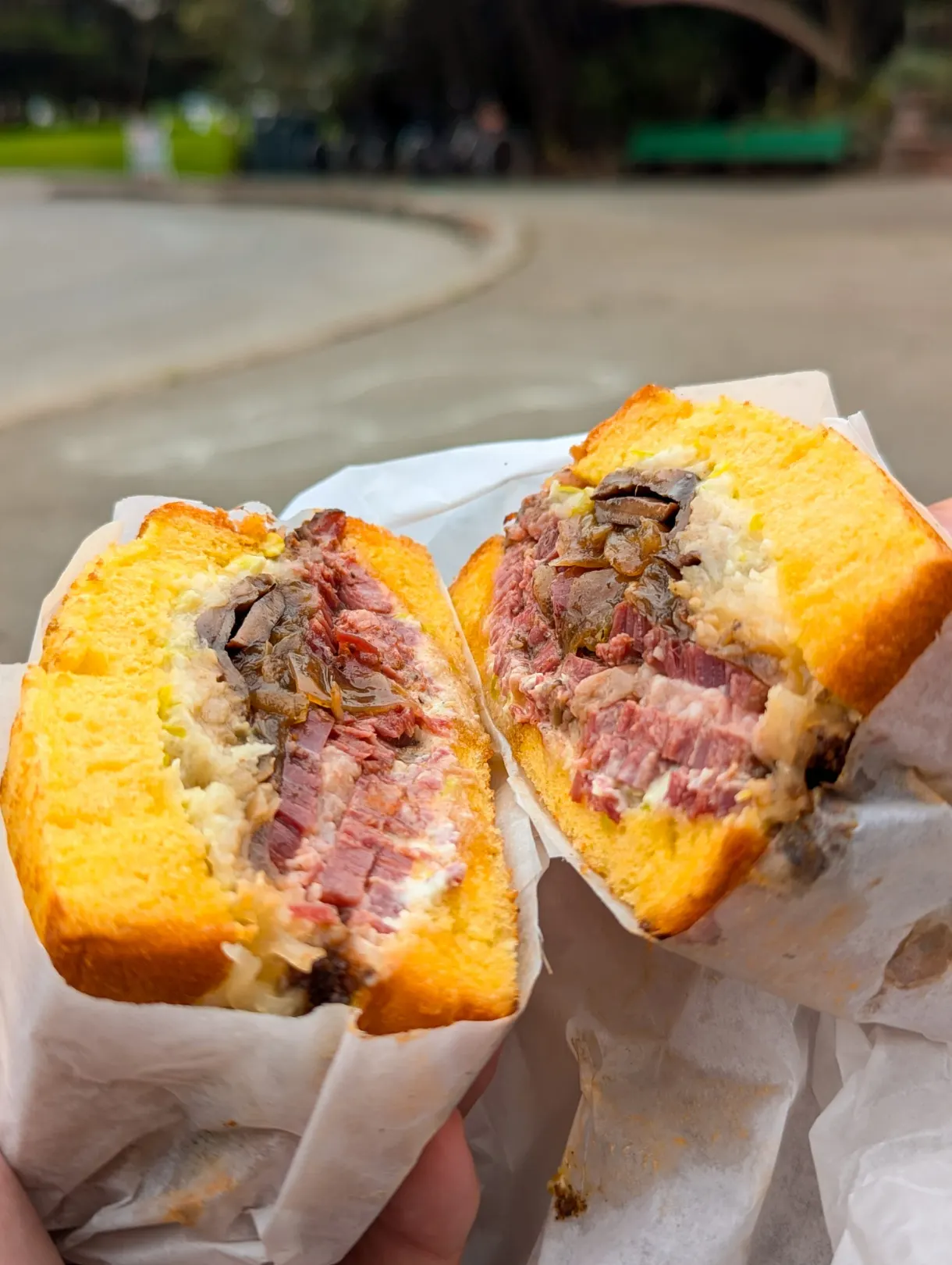 Sandwich au pastrami coupé en deux, tenu à la main