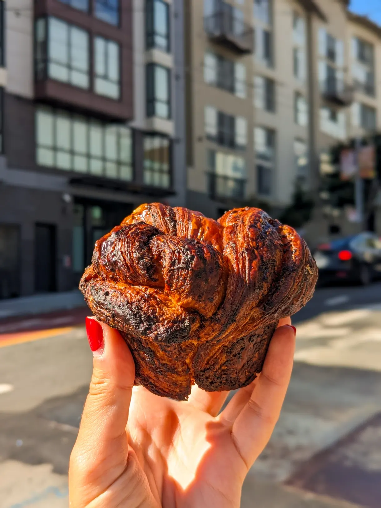 Viennoiserie feuilletée tenue à la main dans une rue