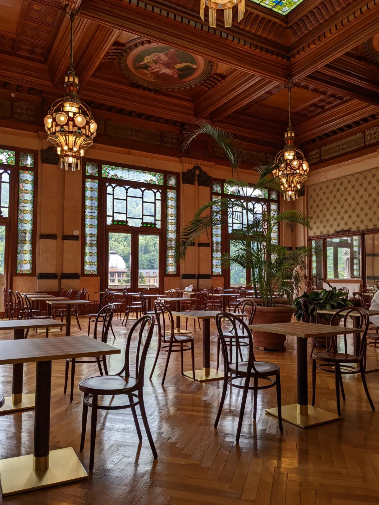 Salle boisée aux lustres anciens et tables rondes