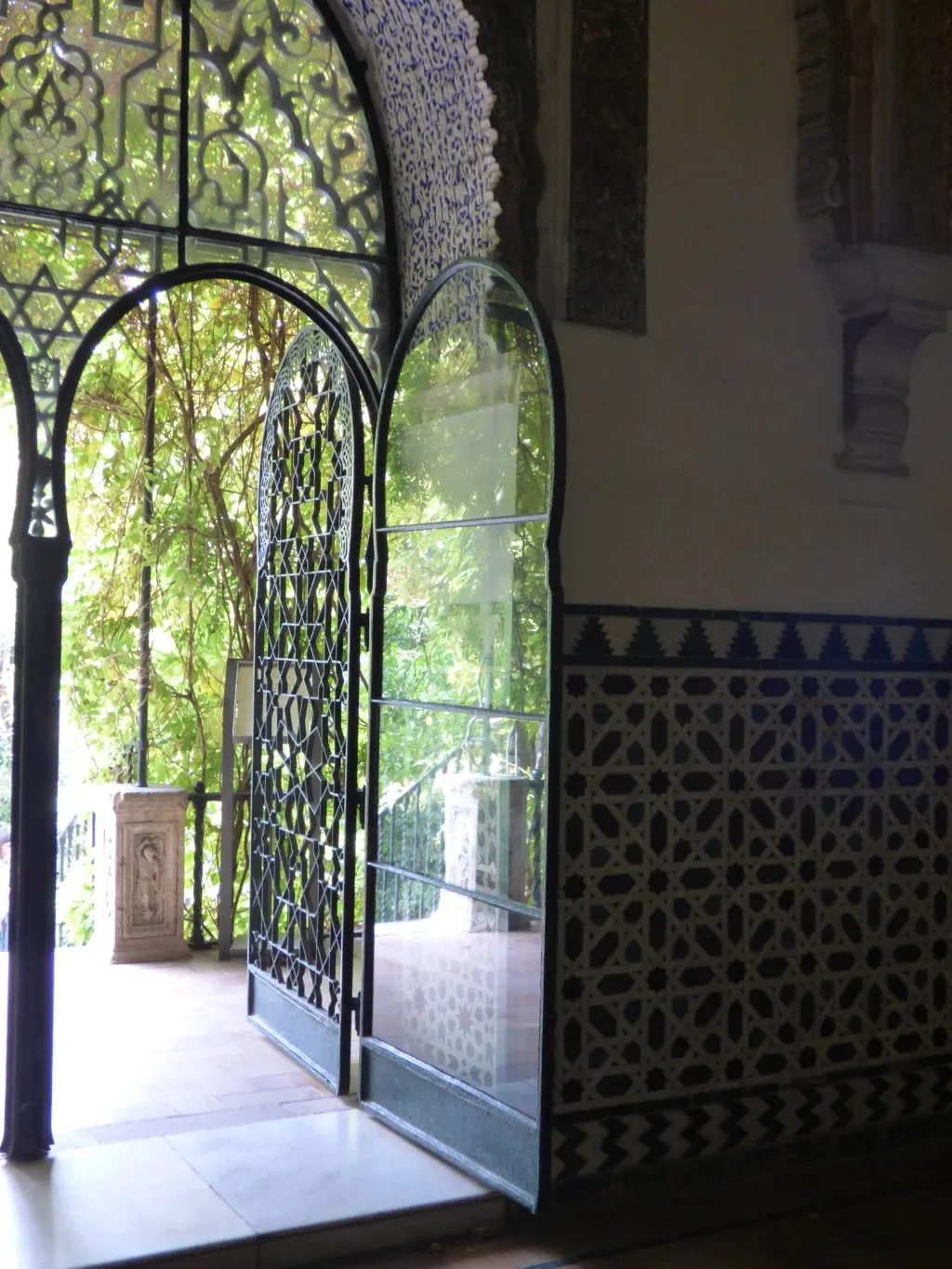 Wrought iron gate open onto the greenery of the garden