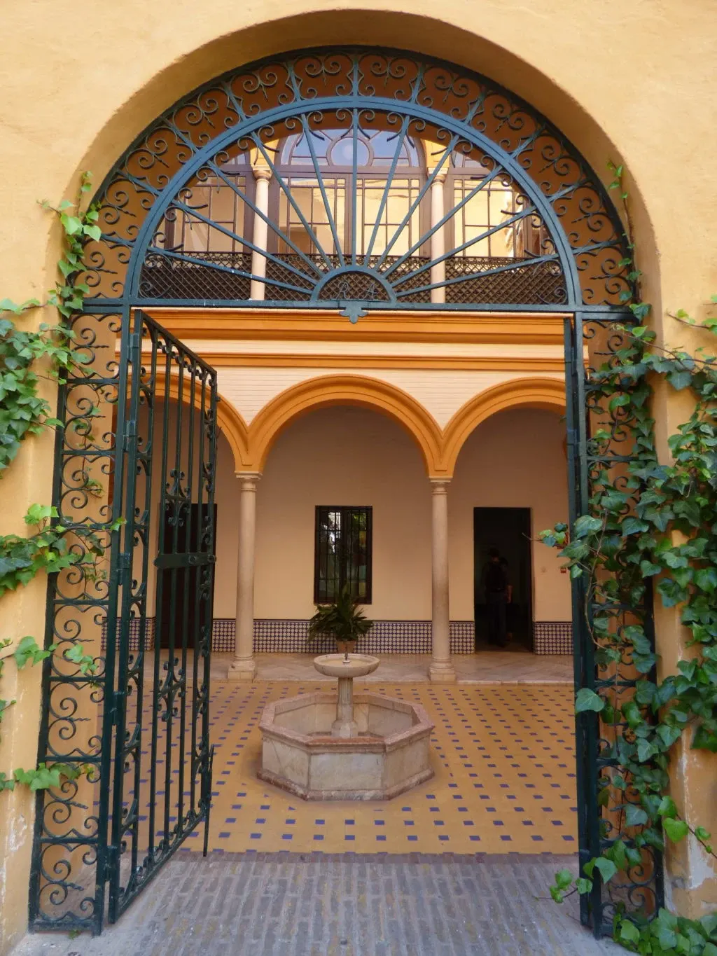 Ornate railing opening onto a patio with a fountain and arcades