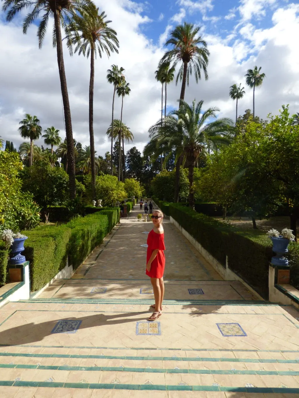 Woman in a red dress on a path lined with palm trees