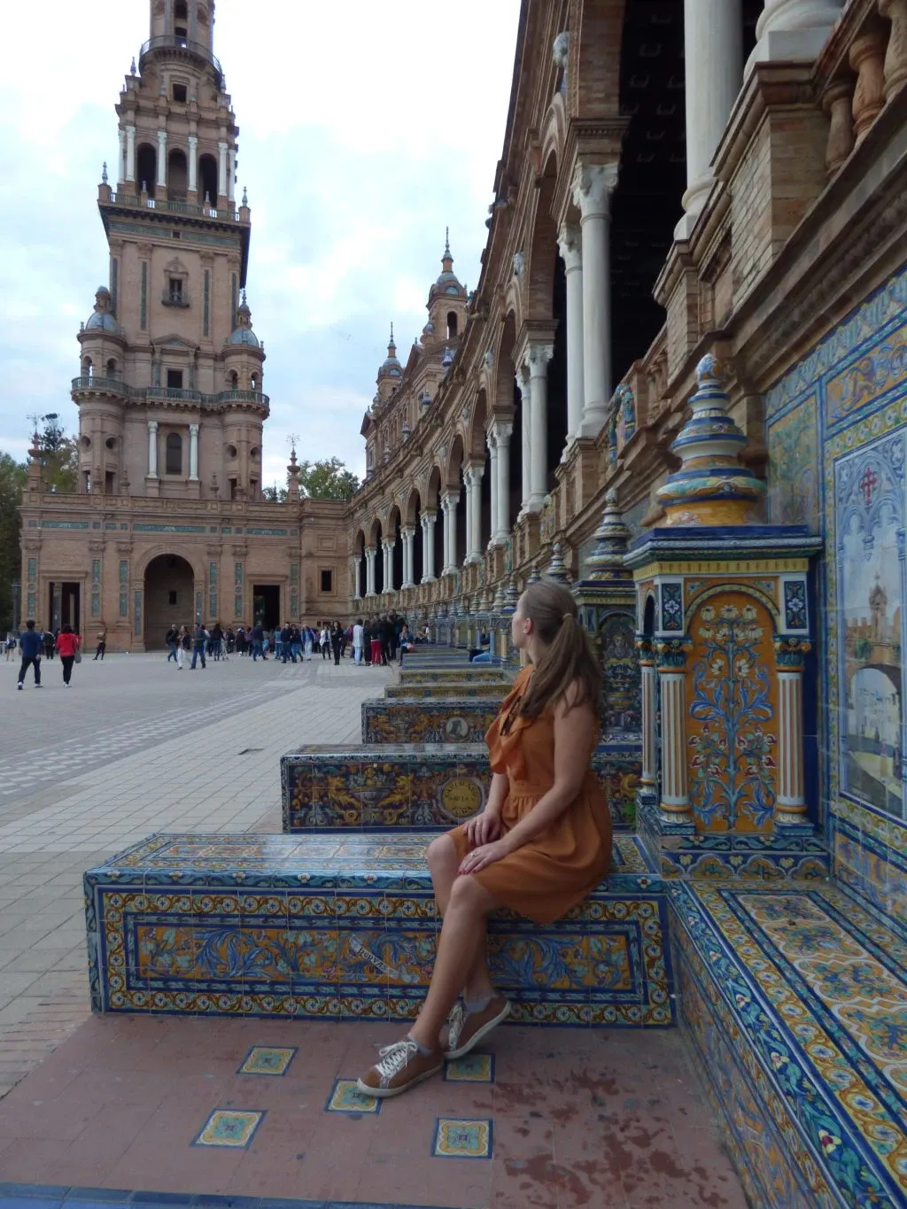 Woman in an ochre dress sitting on an azulejo bench