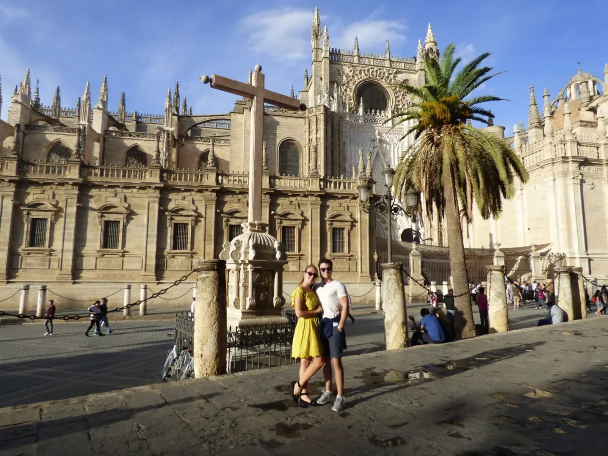 Fountain and palm tree in front of the cathedral, two women posing