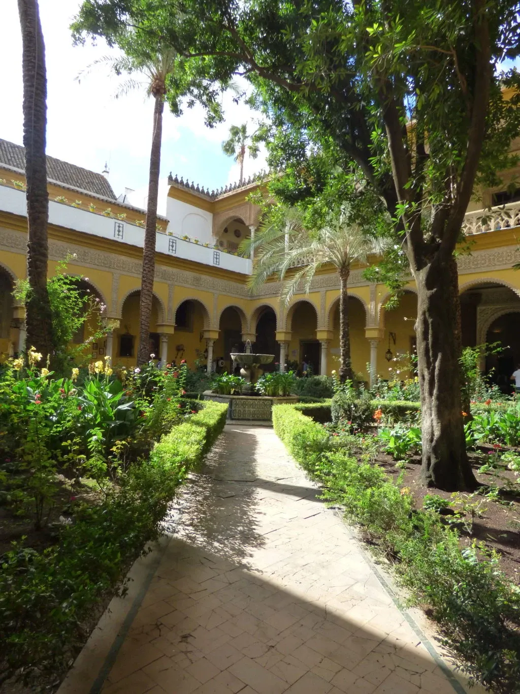 Paved path lined with box, fountain at the far end of the patio
