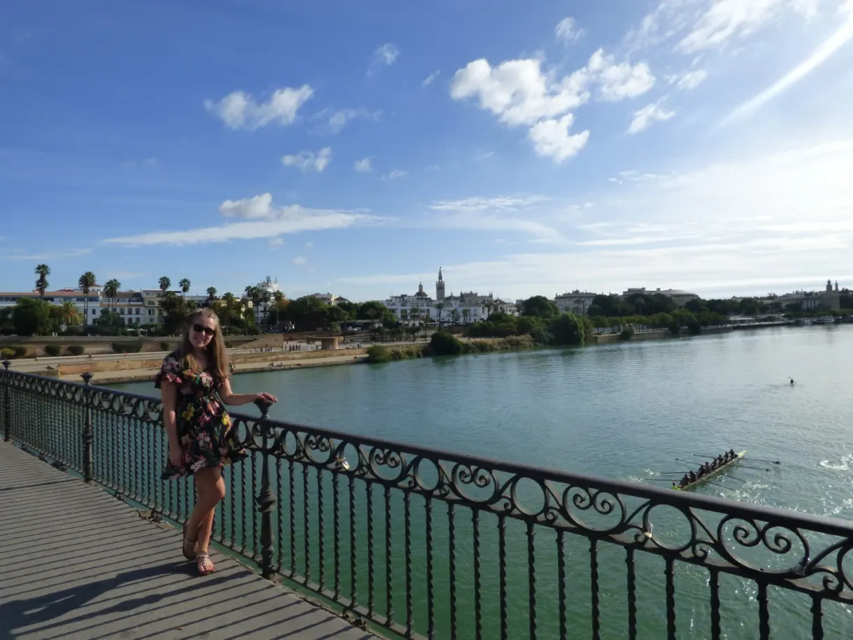 Woman leaning on the railing of a bridge above the river