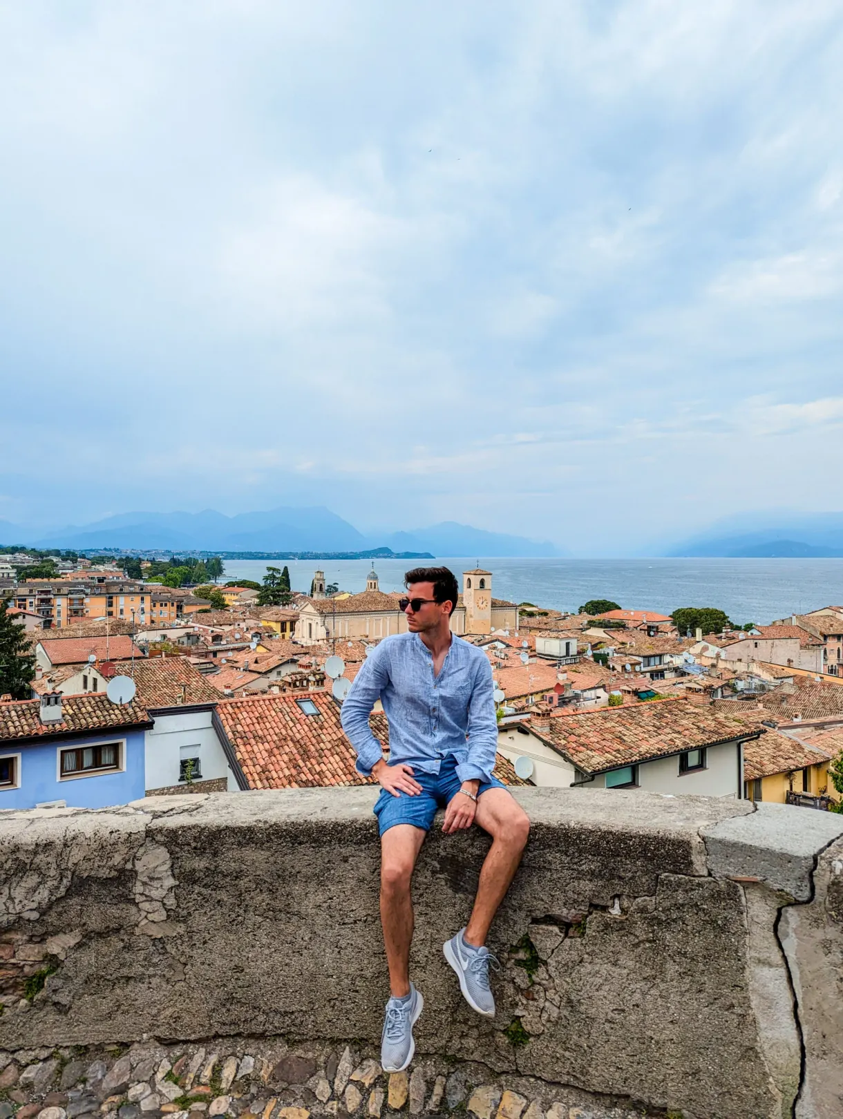 Homme assis sur un muret devant les toits de Desenzano